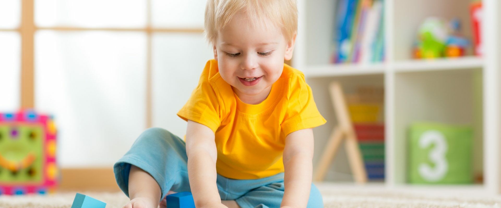 Jak diagnozować i wspierać dzieci z zespołem Aspergera? Wywiad z Joanną Grochowską z Fundacji SYNAPSIS. Mały chłopczyk bawi się klockami w domu.