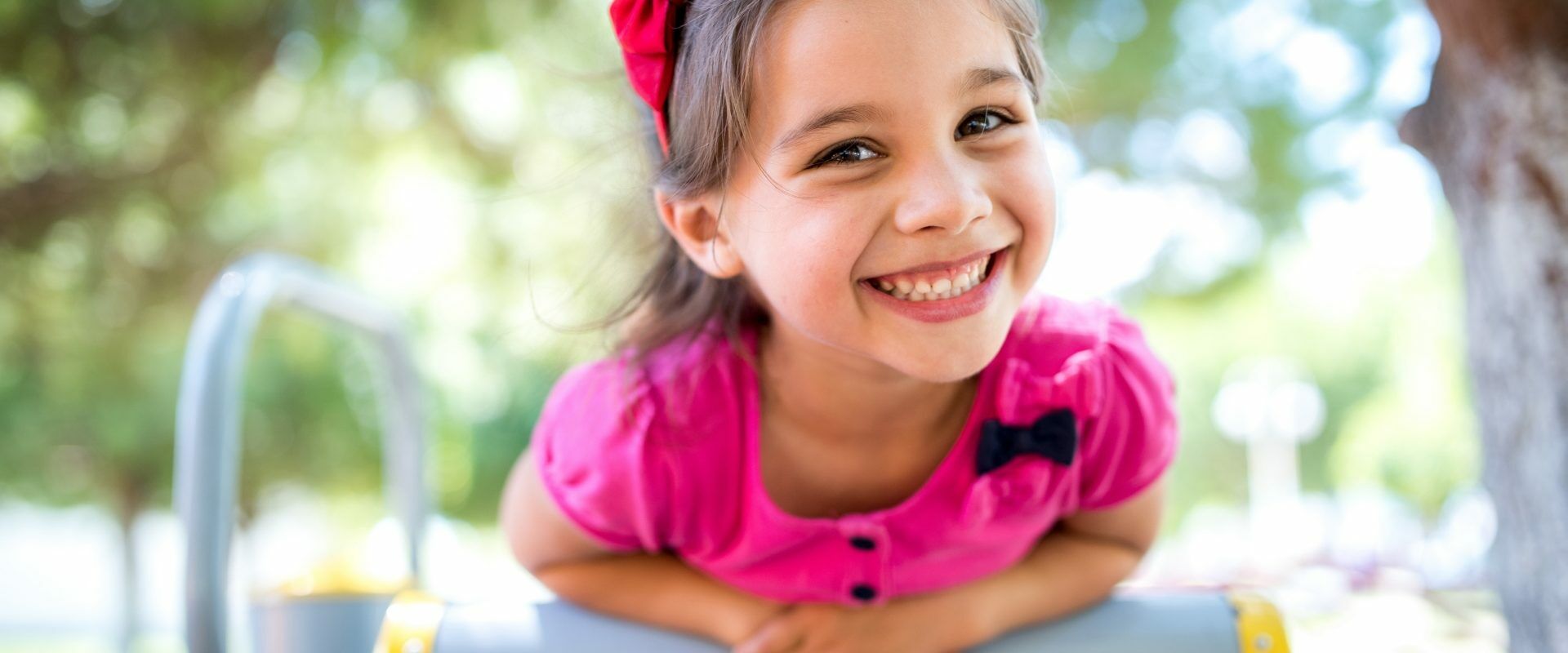 Dr Katarzyna Simonienko o swobodnej zabawie dzieci na świeżym powietrzu. Mała dziewczynka w różowej bluzce bawi się na placu zabaw na dworze latem.